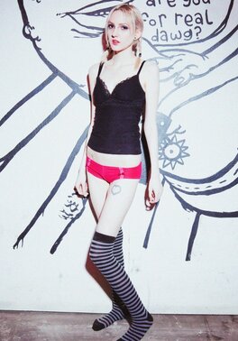 Small-tittied skinny girl in striped over-the-knee socks poses by graffiti wall