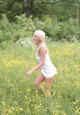 Adorable blonde with juicy tits strips naked in the field full of yellow flowers