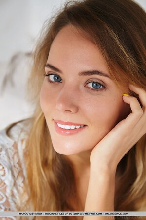 Young model with cute face poses at the photo shoot on the snow-white sofa