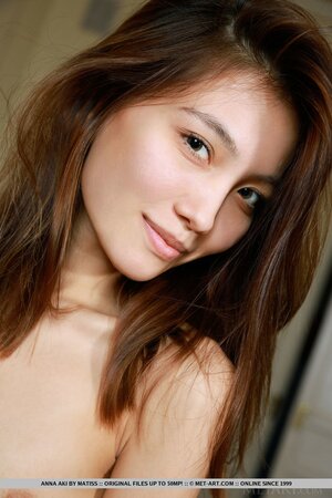 Oriental teen in jeans comfortably sat on the sofa in the run-up to striptease