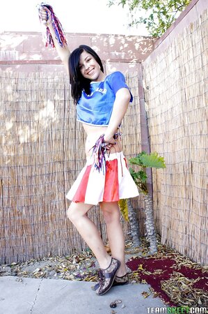 Black-haired cheerleader goes outdoors to perform solo strip show in backyard