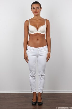 Female with green eyes wears white pants and bra but black panties at photoshoot