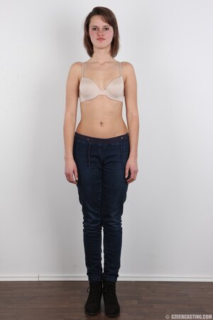 Female smiles so shy but still keeps on stripping naked in photo studio