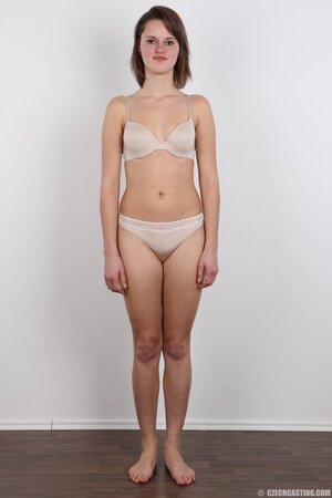Female smiles so shy but still keeps on stripping naked in photo studio