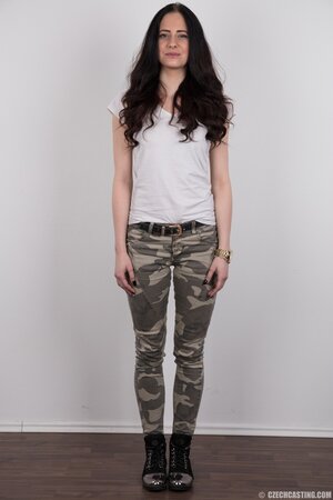 Young woman with black hair takes military pants off showing off her body