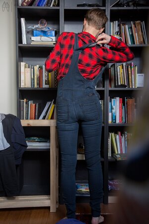 Naked short-haired girl with glasses puts clothes on right in the library