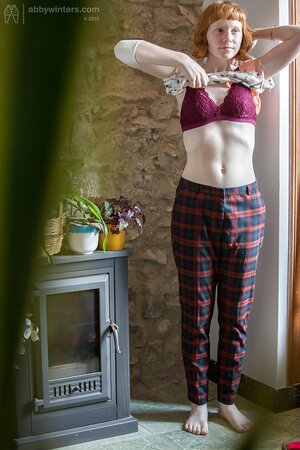 Pale redhead chick covers natural boobs with burgundy lingerie on the spy camera