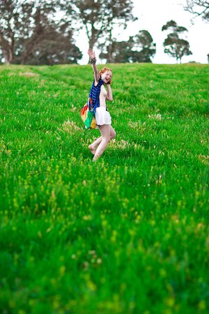 Super-pale ginger lays on the green grass and poses absolutely nude