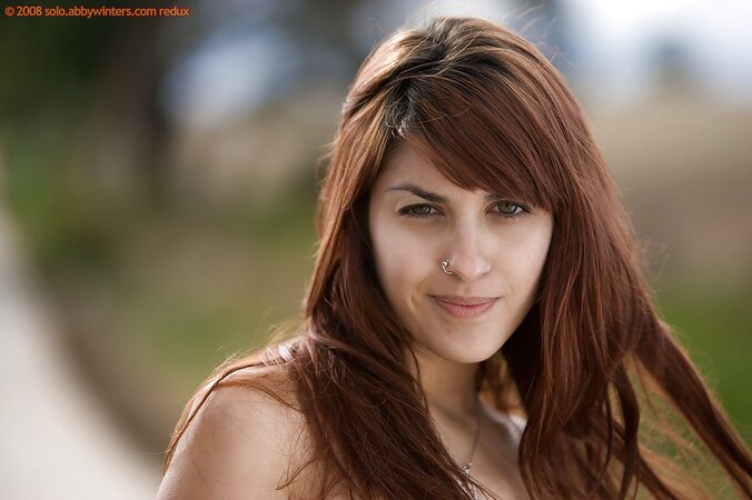 Tall model with red hair disrobes on the path to expose natural breasts