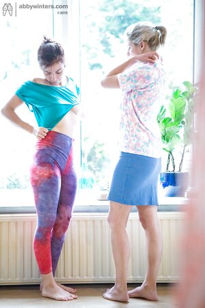 Two leggy dykes put clothes on in front of the window with no shame