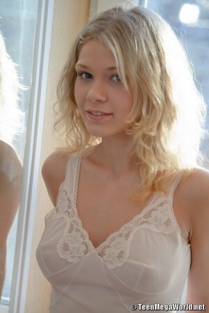 Beautiful blonde with curly hair poses naked for boyfriend by window