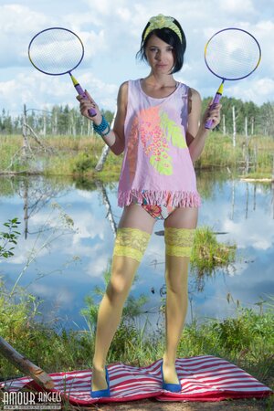 Young woman with black hair waits for partner with two rackets slowly stripping