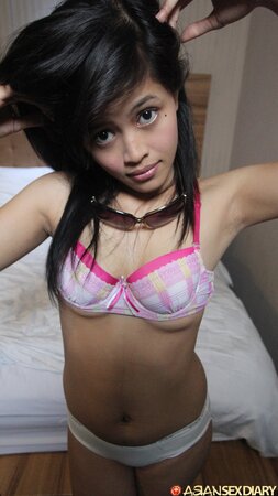 Playful Asian girl gives a kiss exposing tiny boobs and bottom in her bed