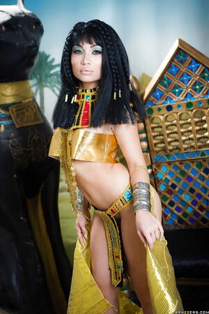 Oriental girl plays the role of Cleopatra posing on a golden throne