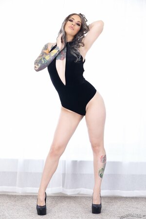 Tattooed MILF relaxes by the window with no clothes but in black high heels