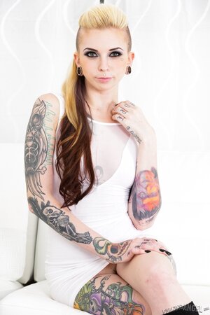 Girl with tattoos wears leg warmers but takes off everything else on a sofa