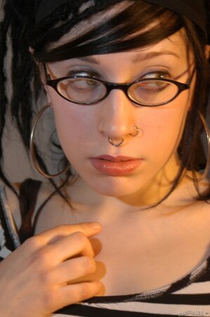 Babe with glasses and pierced nose playfully removes her clothes airing small tits