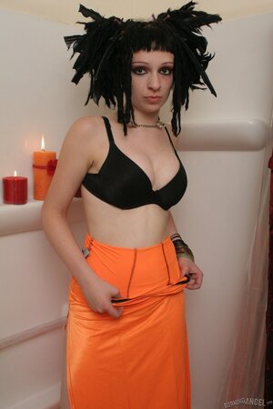 Beautiful female in orange has feathers in her hair and she spreads legs