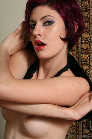 Sybaritic girl with red hair shows off her tattooed wings and handcuffs the hands