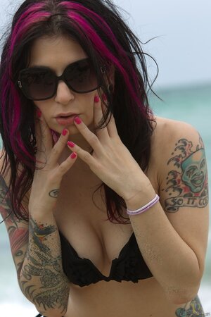 MILF with sunglasses wears black bikini and takes poses in the ocean