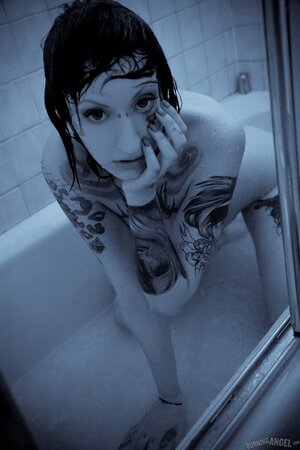 Female with a tattooed body takes a shower and brandishes her private zones