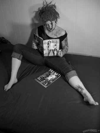Chick with fuzzy hair reads a magazine and masturbates in black and white