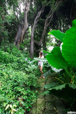 Young cutie shows her neat breasts with plump nipples in the jungle