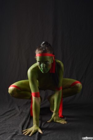Girl in the image of a naked warrior covered in green paint in combat poses