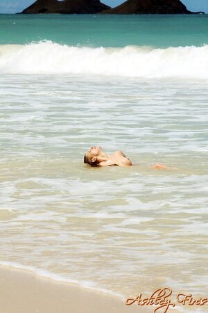 Woman poses on the rocks squirming and shaking her tushy on the ocean shore