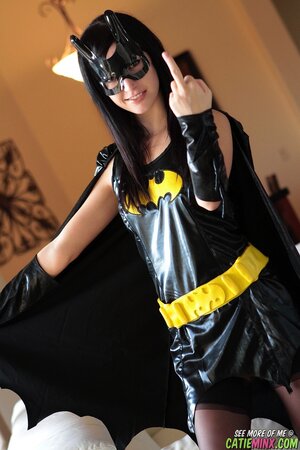 Black-haired fan of cosplay takes off Batman costume and poses naked
