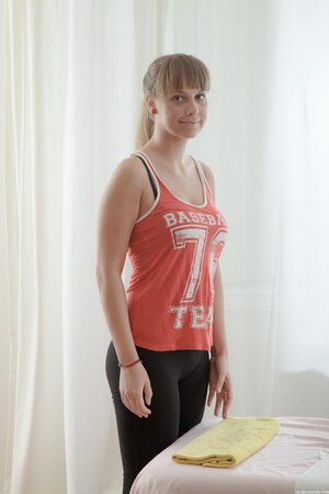 Young woman comes to massage and takes off baseball fan tank top lying down naked