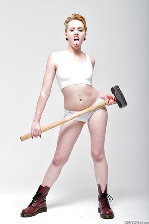 Pale-skinned bitch with short red hair and tongue piercing holds sledgehammer
