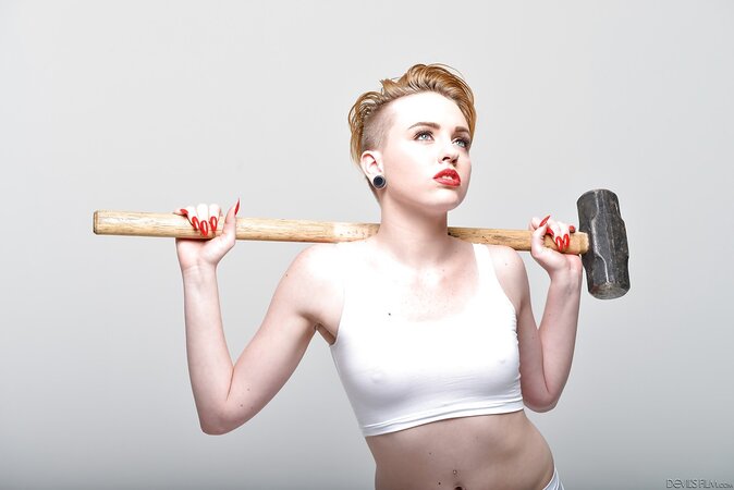Pale-skinned bitch with short red hair and tongue piercing holds sledgehammer