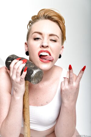 Pale-skinned bitch with short red hair and tongue piercing holds sledgehammer