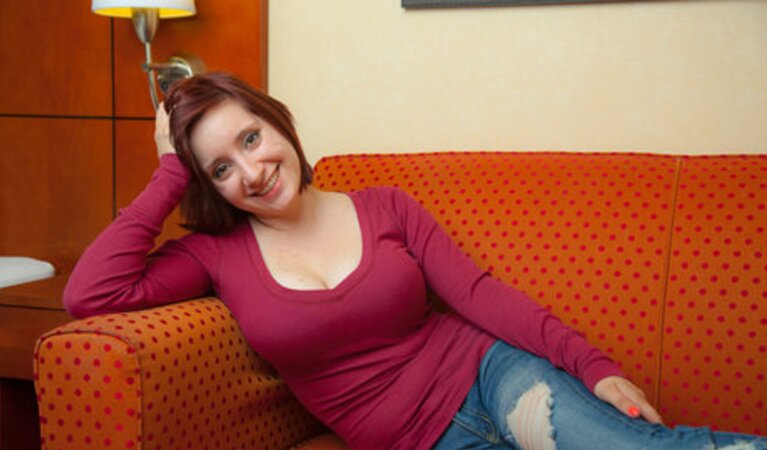 Playful red-haired mom poses topless to reveal her natural melons for the camera
