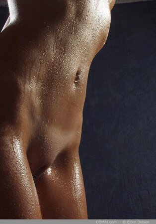 Long-legged girl's body is covered with water before the nude photo session