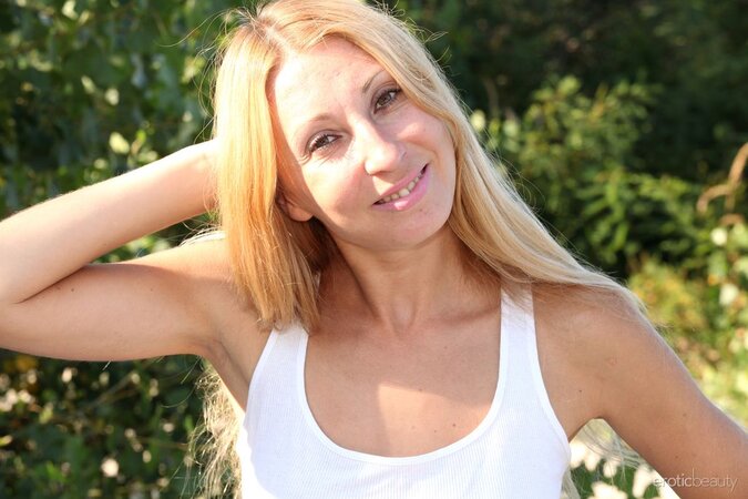 Skinny Latina with blonde hair shows off her partially tanned body on the beach