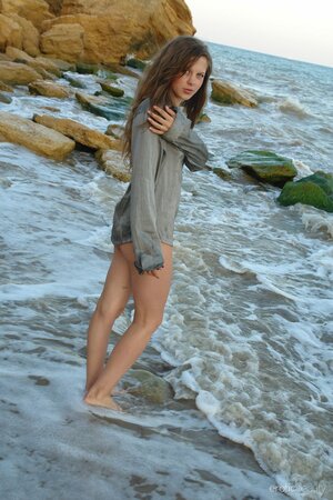 Young sexy cutie gets wet and naked when posing playfully in the sea