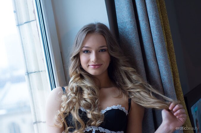 Romantic blonde teen takes off black lingerie while reading on the windowsill