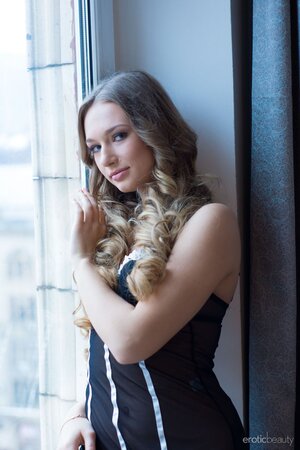 Romantic blonde teen takes off black lingerie while reading on the windowsill