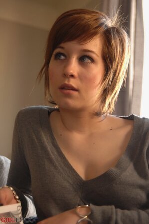 Playful short-haired lassie pulls off sweater to erotically pose in undies