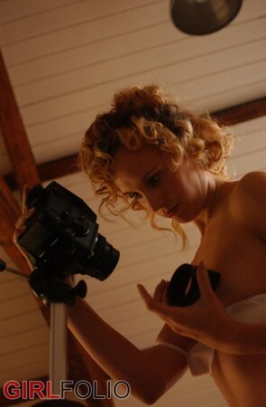 Blonde chick with curly hair takes erotic photos of herself while doffing clothes