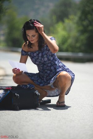 Kinky brunette teases by flashing white panties and nice butt right on the road
