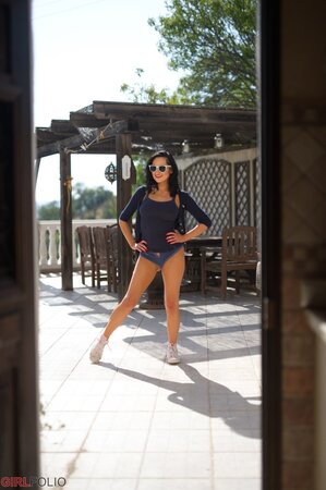 Tempting black-haired bimbo erotically discards clothes to pose naked