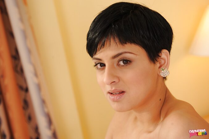 Short-haired young brunette shows off tiny tits and flawless pussy on the bed