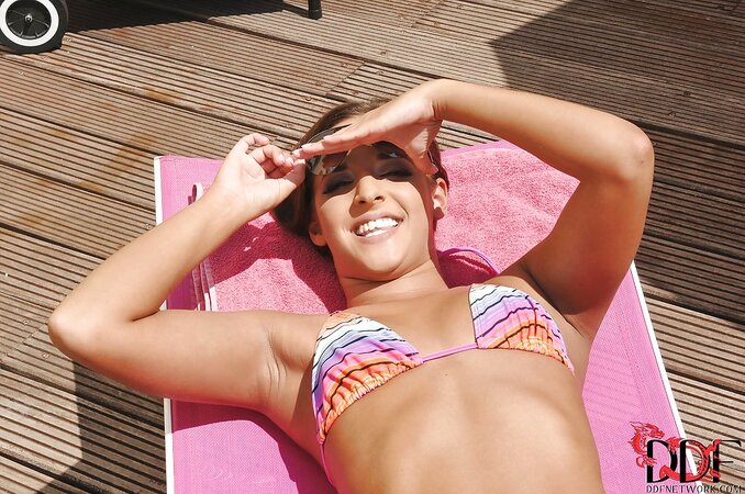 Pretty honey masturbates her smooth pussy while sunbathing by the pool