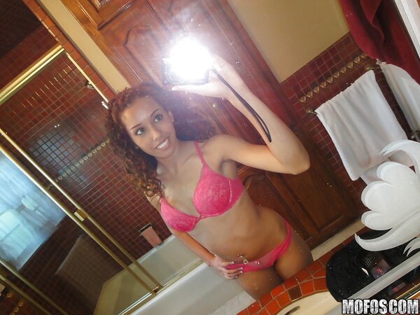 Latina with curly hair is taking sexy selfies while in lingerie
