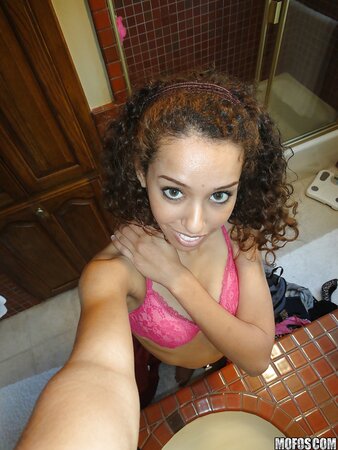Latina with curly hair is taking sexy selfies while in lingerie