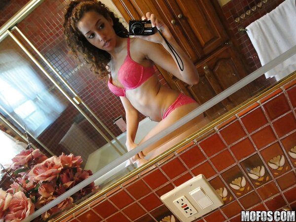 Latina with curly hair is taking sexy selfies while in lingerie