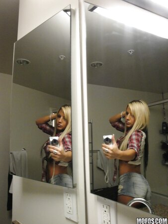 Slim young woman enjoys taking selfie in the bathroom being completely naked